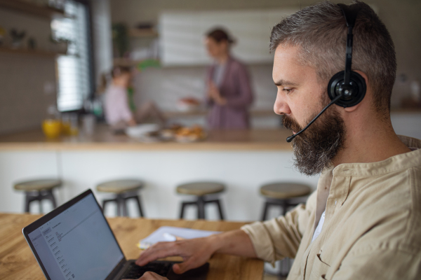 Mature businessman having video call indoors at home, everyday life and home office with child concept.