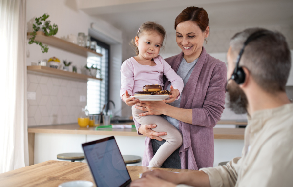 A family with small daughter indoors at home, everyday life and home office with child concept.