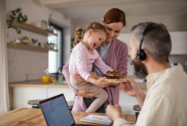 A family with small daughter indoors at home, everyday life and home office with child concept.