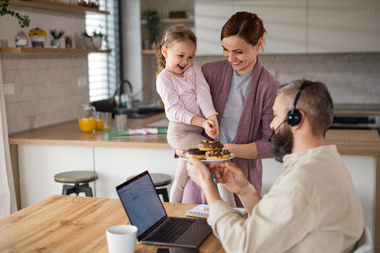 A family with small daughter indoors at home, everyday life and home office with child concept.