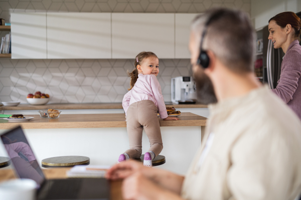 Mature businessman having video call indoors at home, everyday life and home office with child concept.