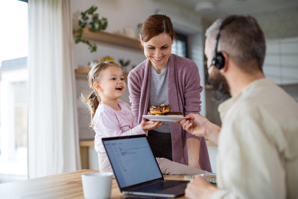 A family with small daughter indoors at home, everyday life and home office with child concept.