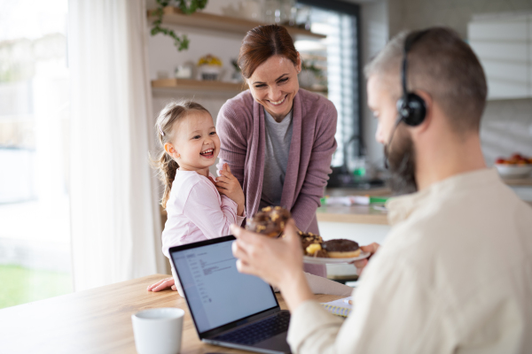 A family with small daughter indoors at home, everyday life and home office with child concept.