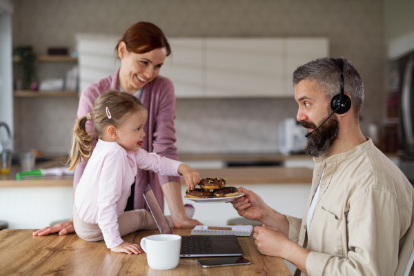 A family with small daughter indoors at home, everyday life and home office with child concept.