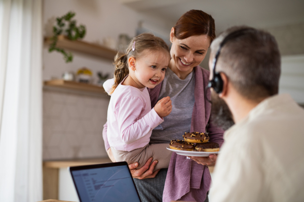 A family with small daughter indoors at home, everyday life and home office with child concept.