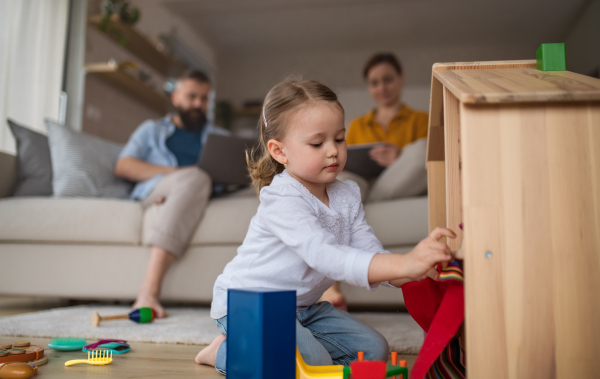 A little girl playing indoors at home, everyday life and home office with child concept.