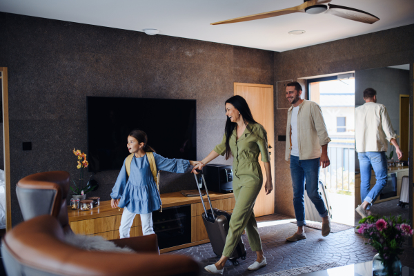 A happy young family with two children enetring room at luxury hotel, summer holiday.