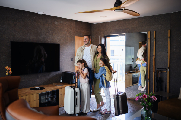 A happy young family with two children enetring room at luxury hotel, summer holiday.