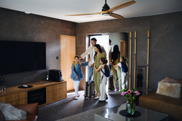 A happy young family with two children enetring room at luxury hotel, summer holiday.