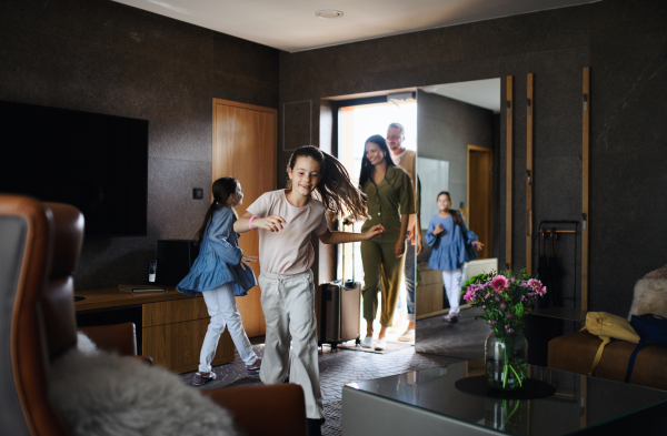 A happy young family with two children enetring room at luxury hotel, summer holiday.