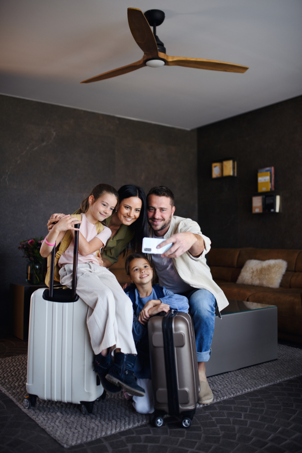 A happy young family with two children taking selfie at luxury hotel, summer holiday.