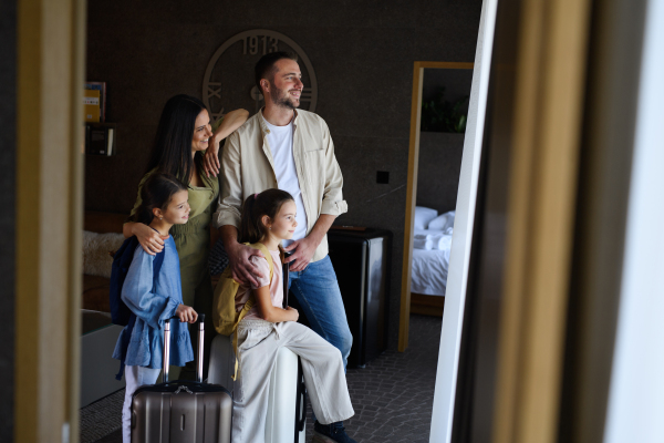 A happy young family with two children enetring room at luxury hotel, summer holiday.