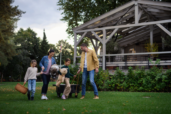 A happy young family with basket and blanket going to have picnic outdoors in restaurant area.