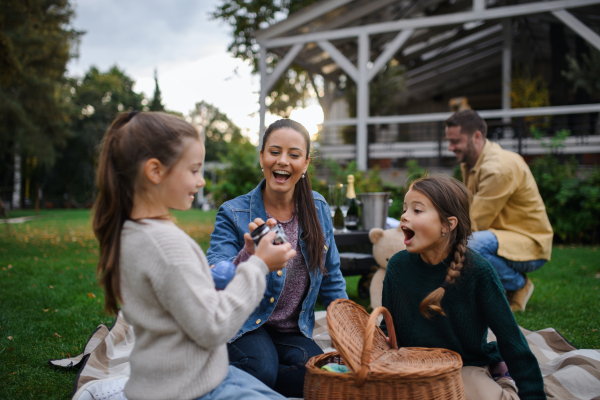 A happy young family sitting on blanket and having take away picnic outdoors in restaurant area.