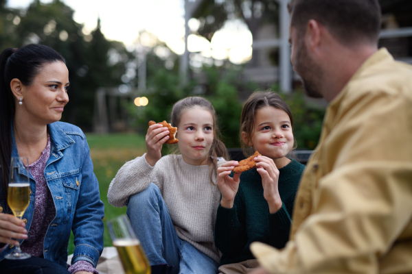 A happy young family sitting on blanket and having take away picnic outdoors in restaurant area.