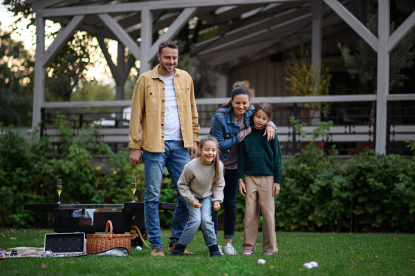 A happy young family with basket and blanket going to have picnic outdoors in restaurant area.