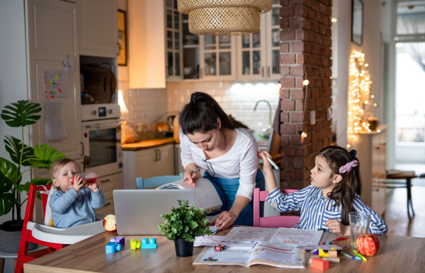 Portrait of mother with small daughter in kitchen, home schooling, office and distance learning concept.