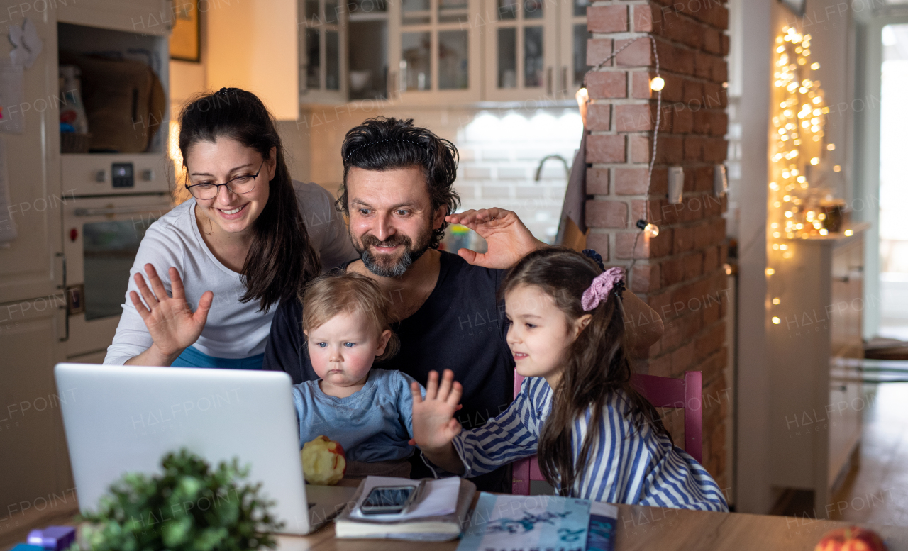 Happy family with small daughters in kitchen, distance learning, video call with family or friends.