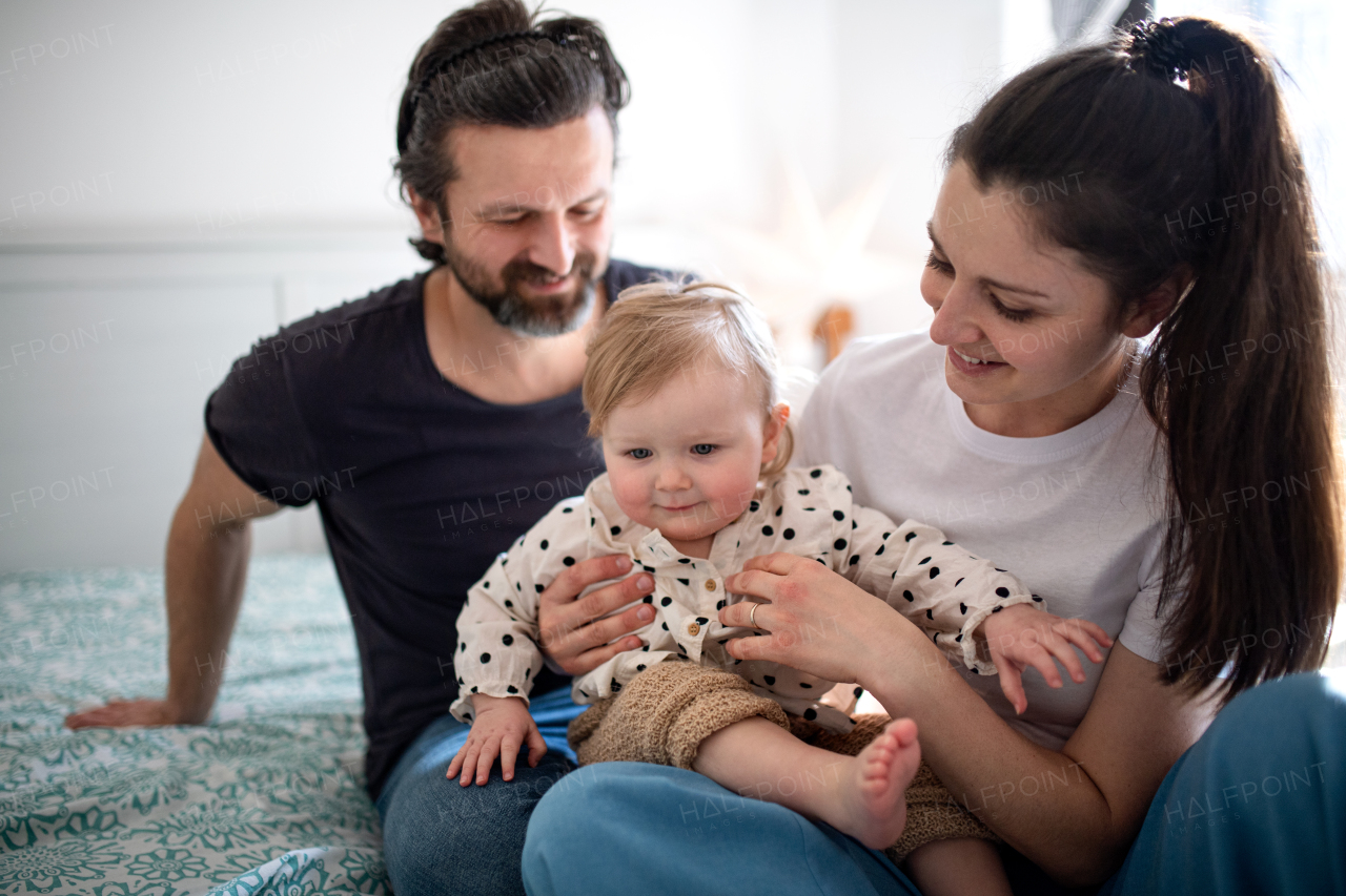 Portrait of happy family with two small daughters having fun on bed at home.