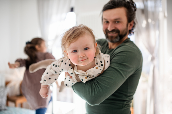 Portrait of happy father with two small daughters having fun indoors at home.