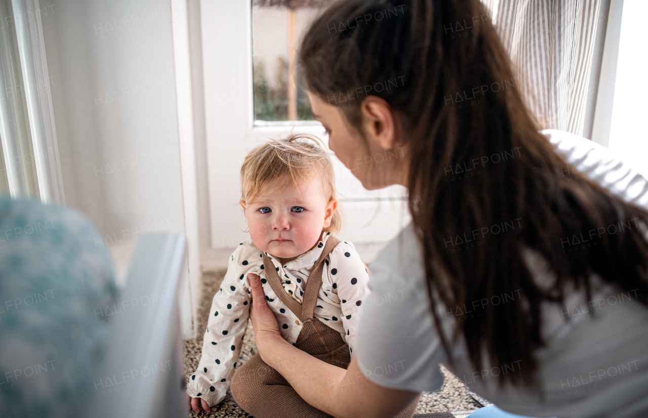 A mother with small toddler daughter in bedroom at home.