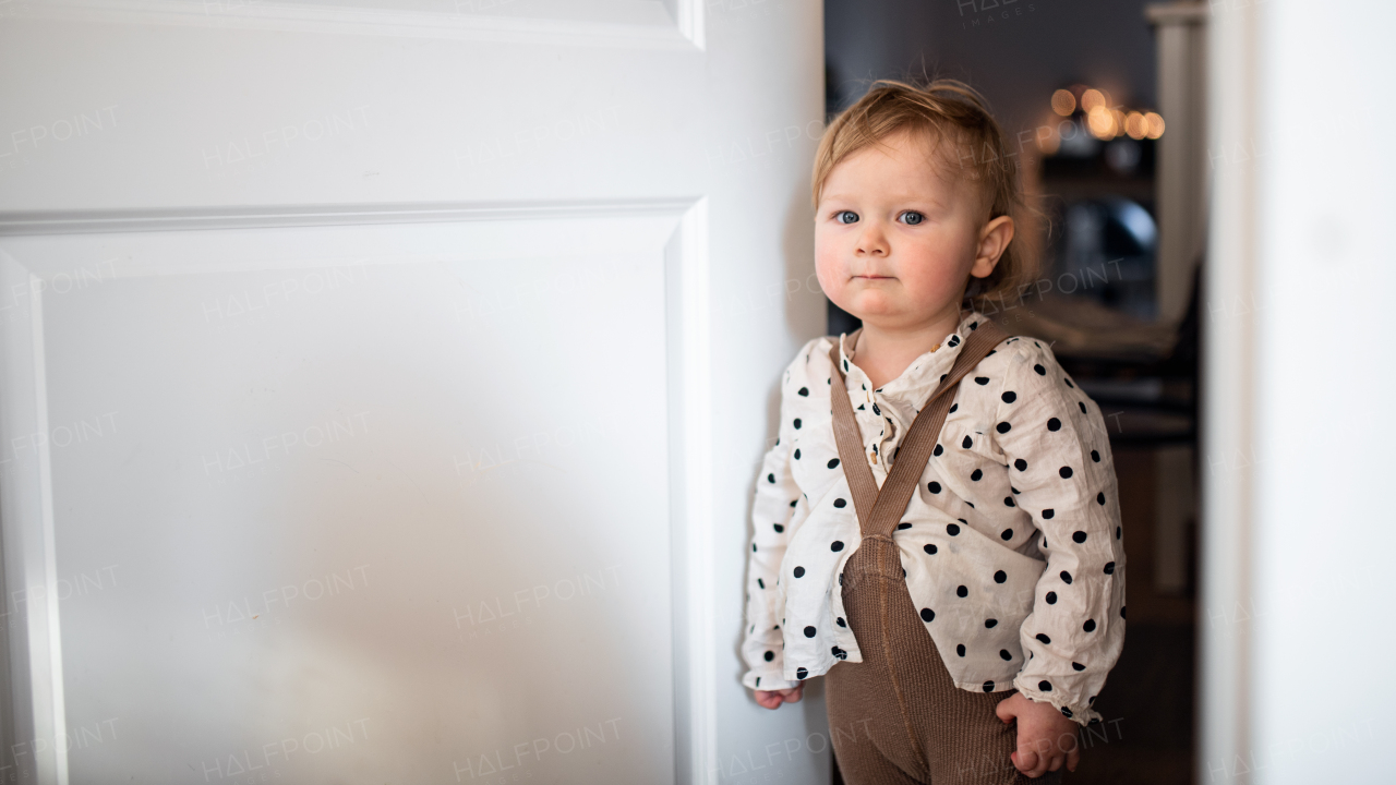 Portrait of small toddler girl in bedroom at home, looking at camera. Copy space.