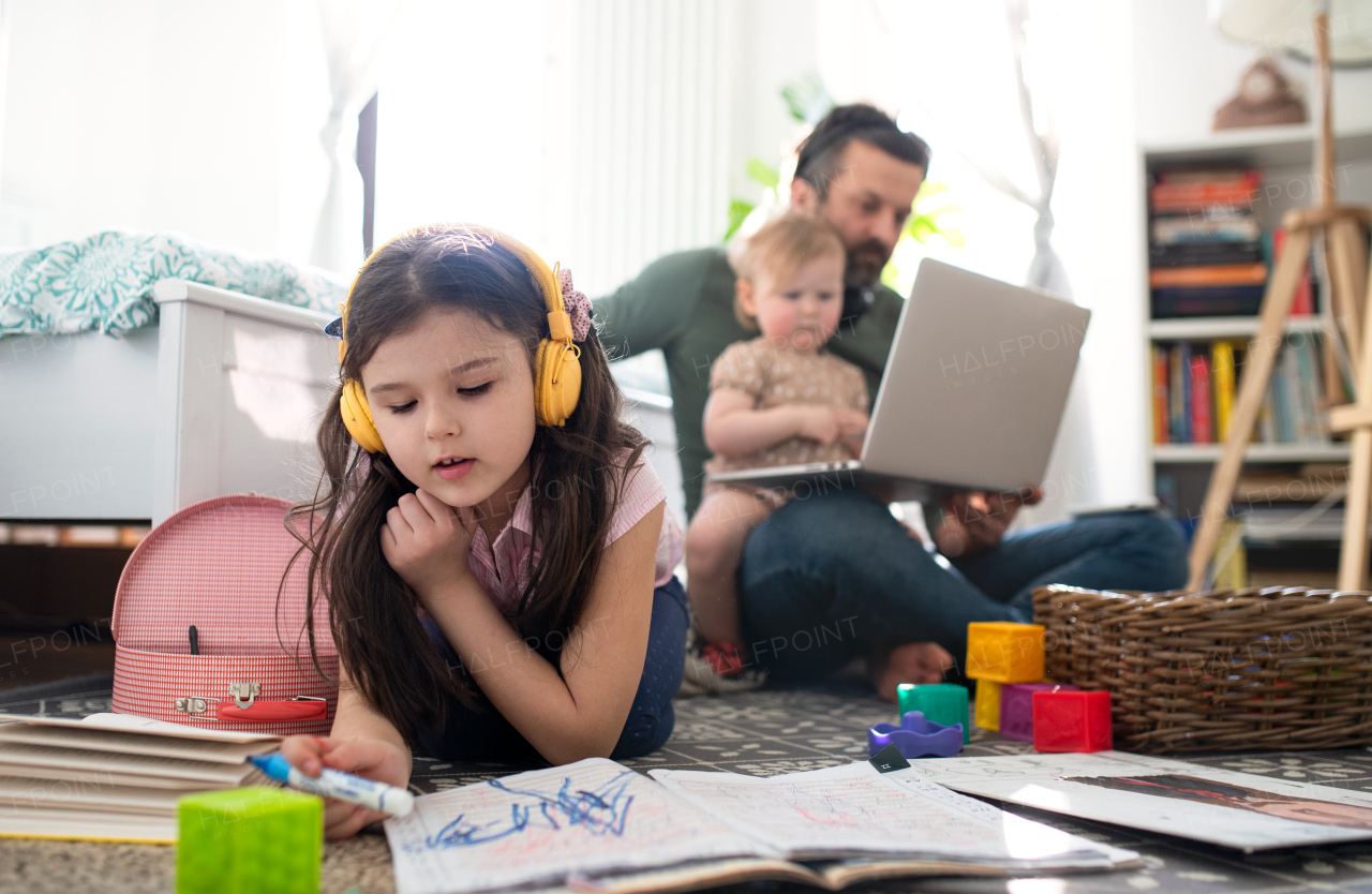 Busy father working with small daughters in bedroom, home office concept.