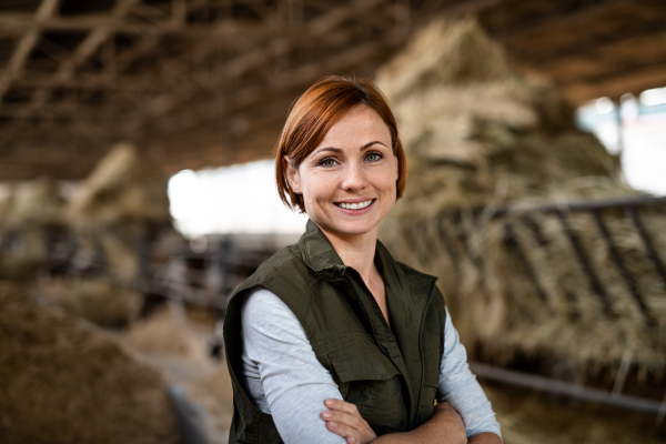 Woman worker standing on diary farm, looking at camera. Agriculture industry.