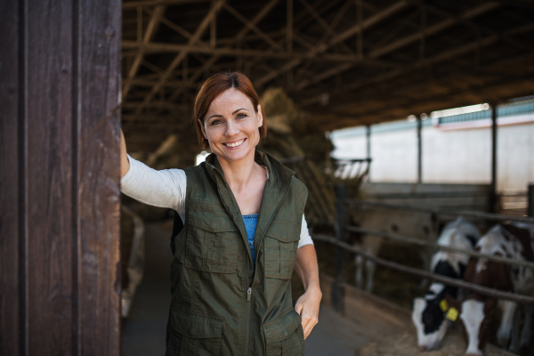 Woman worker standing on diary farm, looking at camera. Agriculture industry.