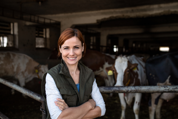 Woman worker standing on diary farm, looking at camera. Agriculture industry.