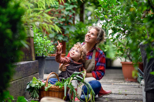 Happy mother with small daughter gardening on farm, growing organic vegetables.