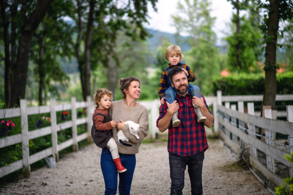 Portrait of happy family with small children walking on farm.