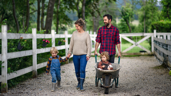 Portrait of happy family with small children walking on farm.