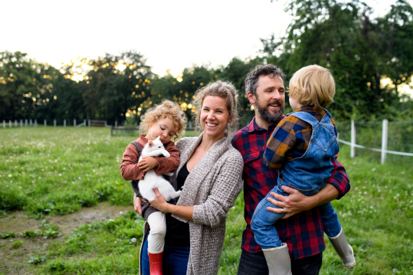 Portrait of happy family with small children standing on farm, resting.