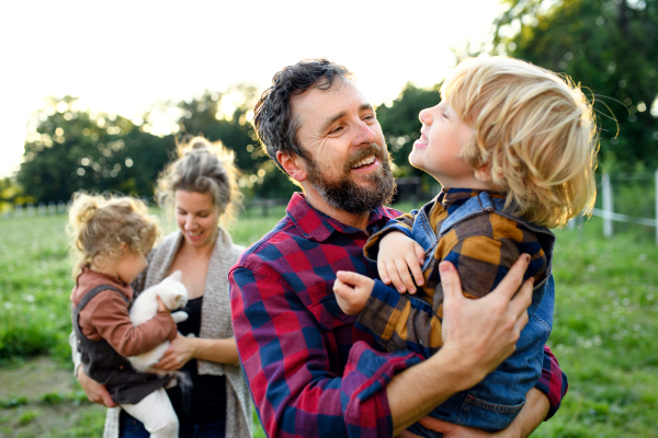 Portrait of happy family with small children standing on farm, resting.