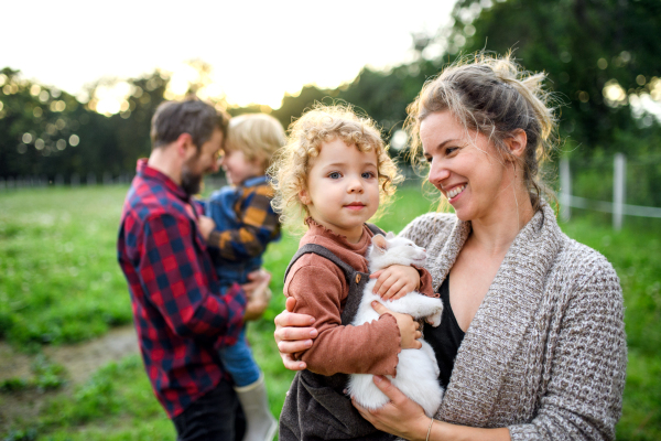 Portrait of happy family with small children standing on farm.