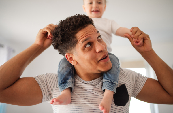 Cheeful father and small toddler son indoors at home, playing.