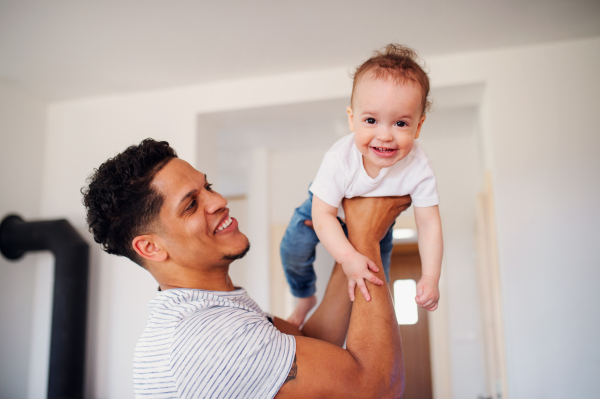 A portrait of cheerful father and small toddler son indoors at home, playing.