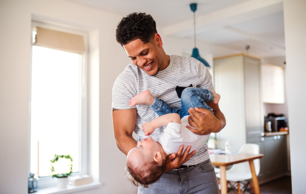 A portrait of cheerful father and small toddler son indoors at home, playing.