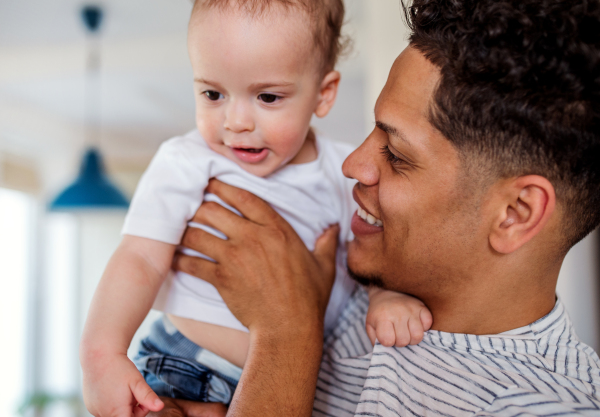 A portrait of cheerful father and small toddler son indoors at home, playing.