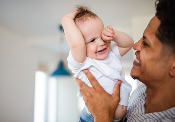 A portrait of cheerful father and small toddler son indoors at home, playing.