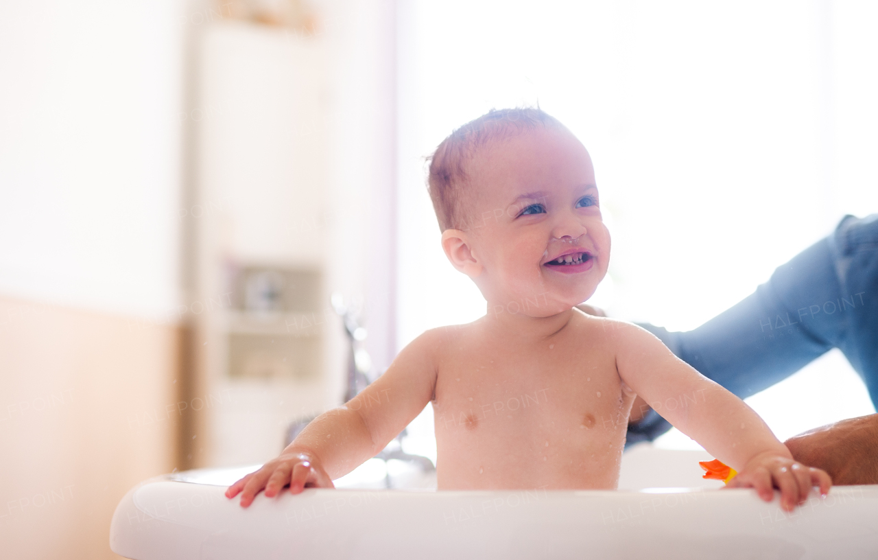 Unrecognizable father washing happy small toddler son in a bathroom indoors at home.