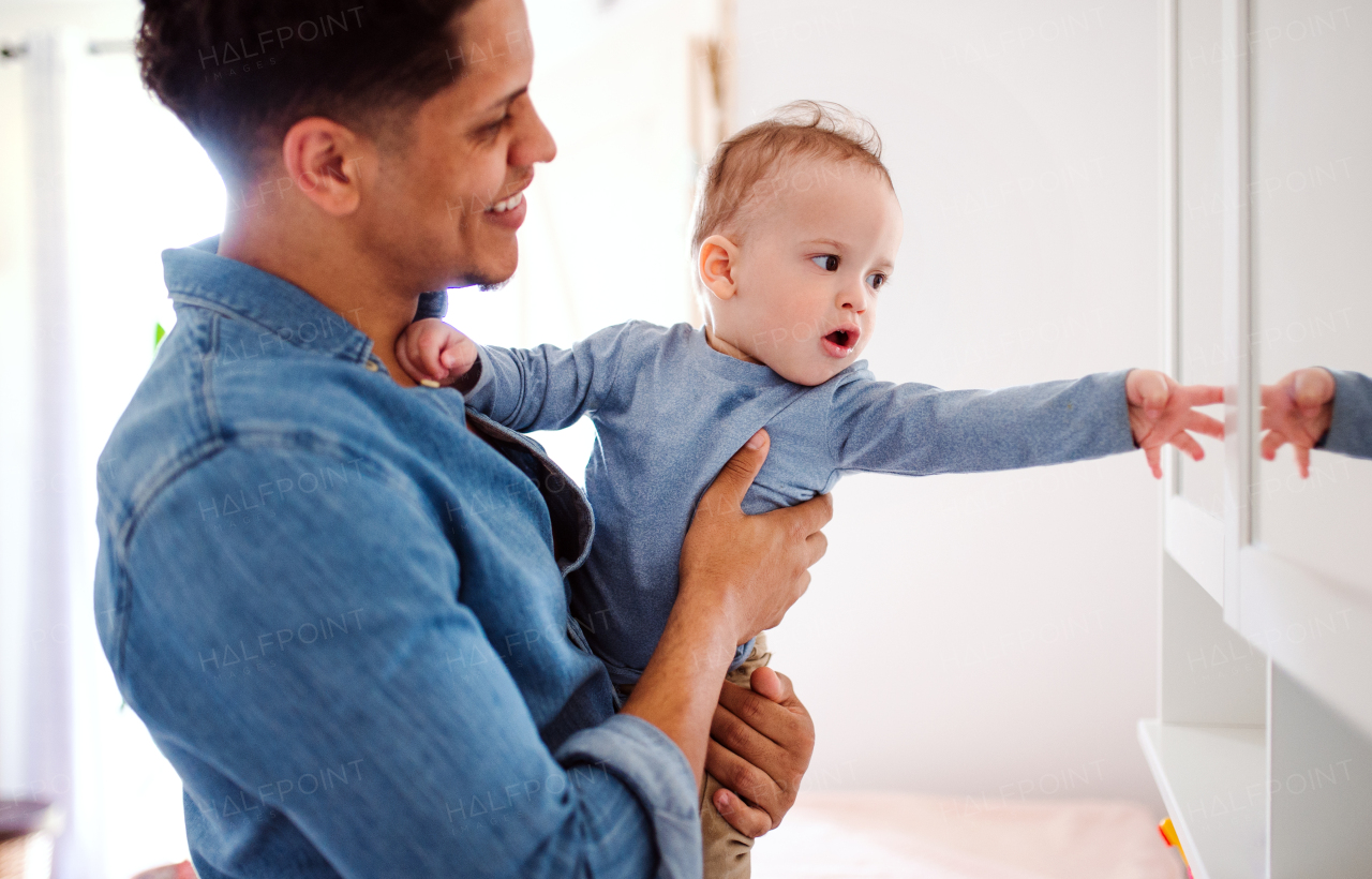 A portrait of cheerful father and small toddler son indoors at home, playing.