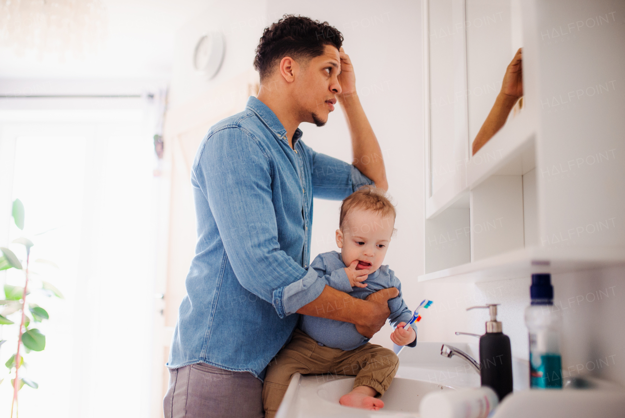 Young father and small toddler son in a bathroom indoors at home, washing.