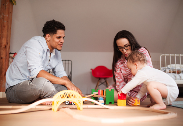 A young family with small toddler son indoors at home, playing.