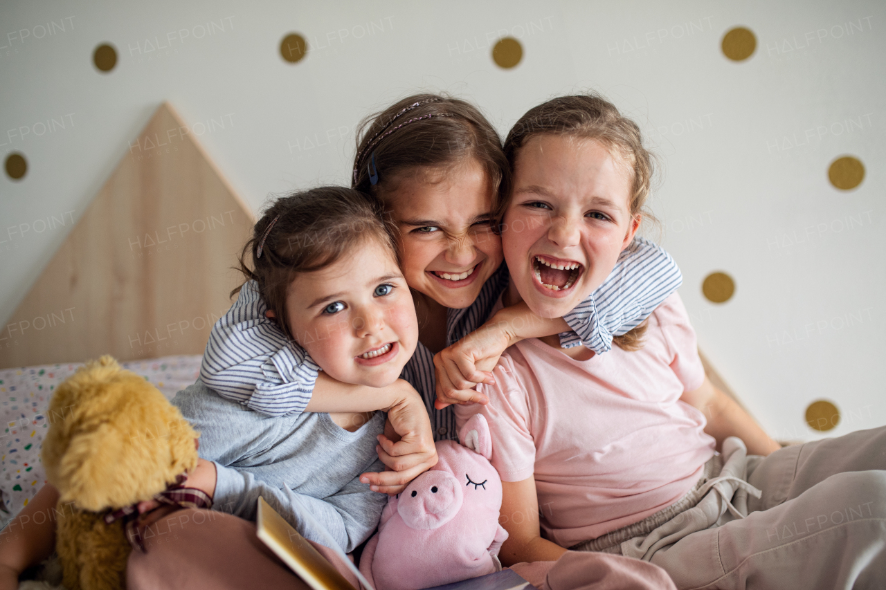 A portrait of three girls sisters indoors at home, looking at camera.