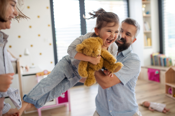 A father with daughters indoors at home, playing, laughing and having fun.