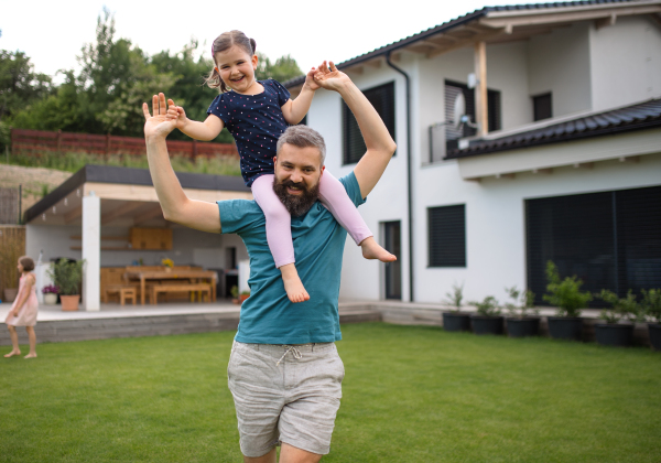 A father with daughters playing outdoors in the backyard, running.