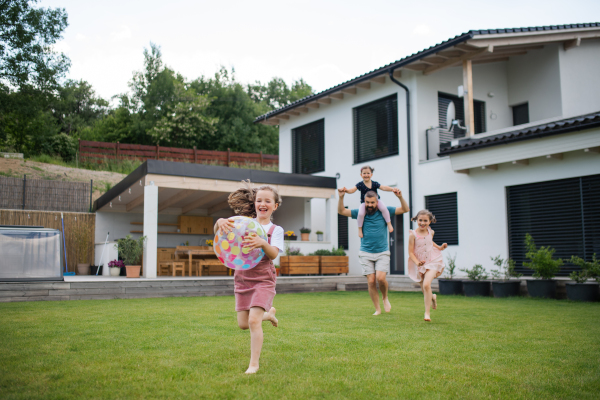 A father with three daughters playing outdoors in the backyard, running.