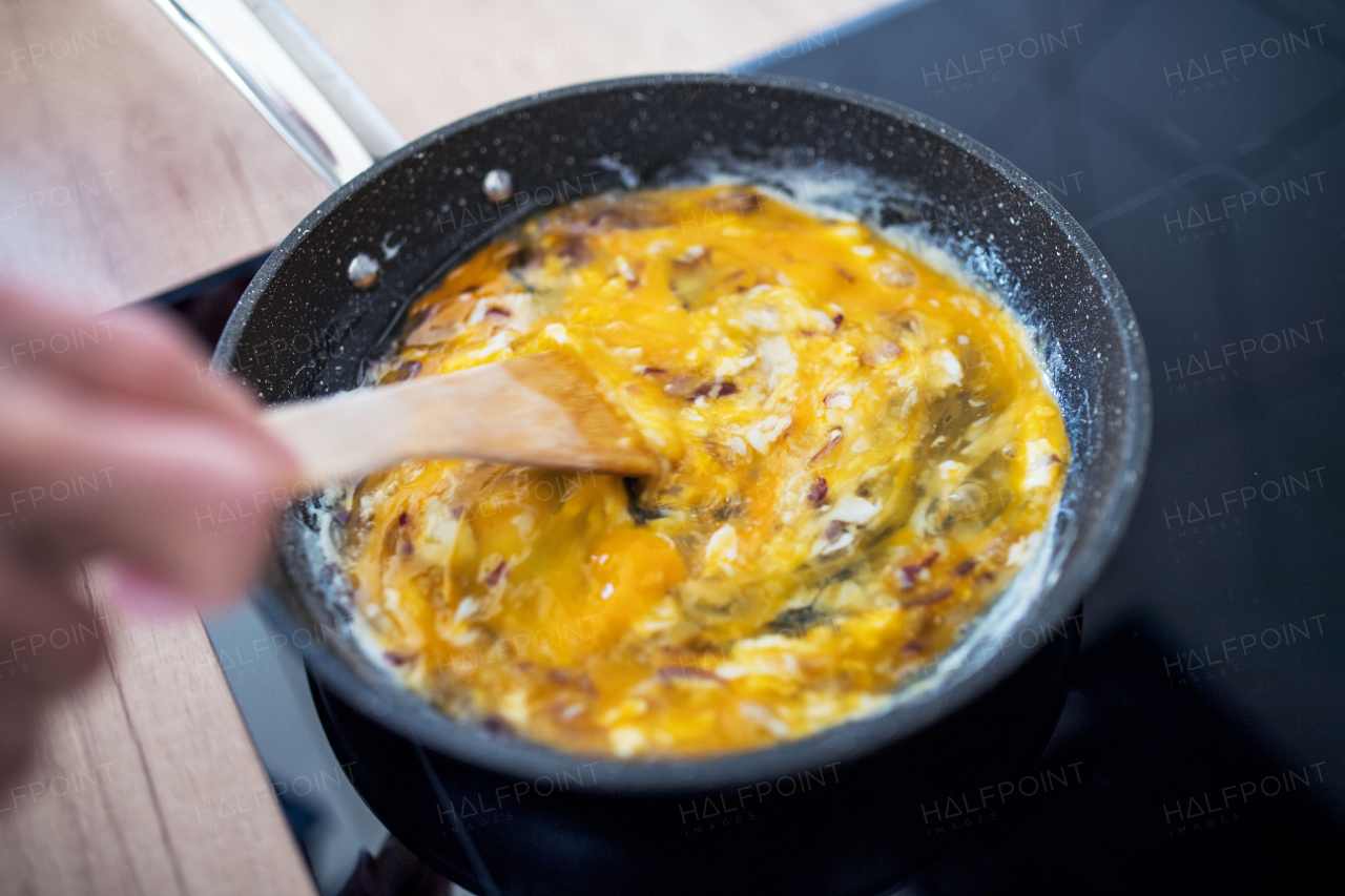 A close-up of cooking scrambled eggs on pan indoors at home.